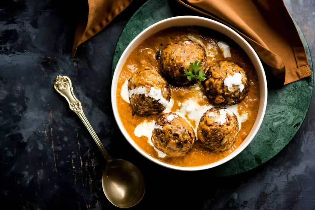 Malai Kofta is a Mughlai Speciality dish served in a bowl or pan over moody background